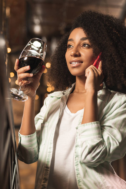 Beautiful young woman having wine and talking on phone - Photo, image