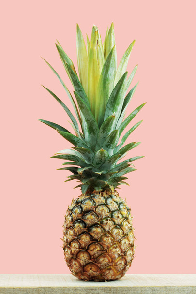 Verse ananas op houten met een roze achtergrond. - Foto, afbeelding