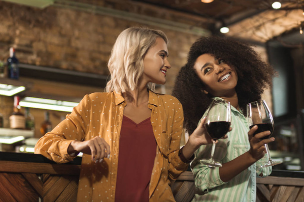 Upbeat female friends drinking wine in the bar - Foto, imagen
