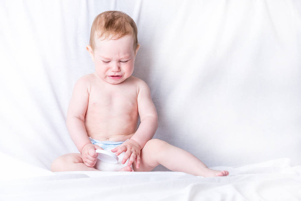 Lindo bebé de ojos azules 6-9 meses de edad triste llanto fondo blanco. Las emociones de los niños. El dolor de la dentición
 - Foto, Imagen