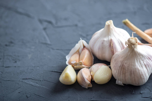 Group of garlic cloves scattered on a table on a white background. An important ingredient in different cuisines of the world. A healthy product. - Photo, Image