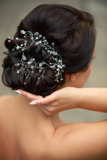 Hairstyle for the wedding. Back view. The bride adjusts her hair. Wedding manicure. - Φωτογραφία, εικόνα