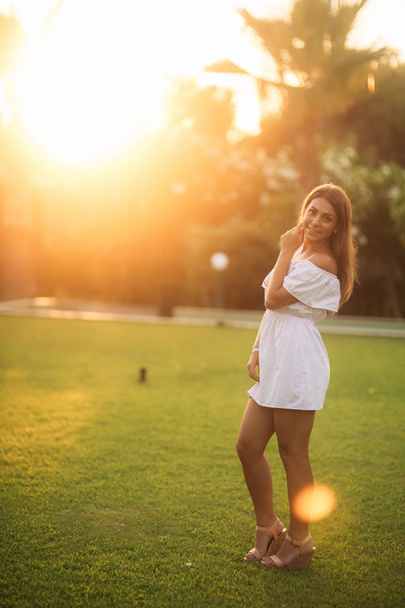 Lady in white dress near the palm in summer time - Foto, afbeelding