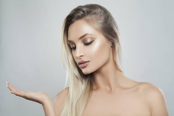 Young Perfect Woman with Natural Makeup, Healthy Skin and Blonde Hair Showing Empty Copy Space on the Open Hand. Facial treatment, Cosmetology, Beauty, Skincare and Spa - Φωτογραφία, εικόνα