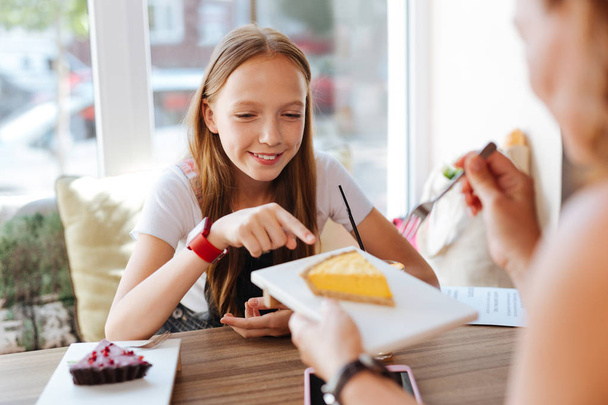 Smiling teenager trying cheesecake with her mother - Foto, Imagem