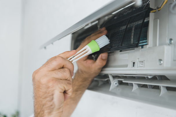 cropped view of male worker cleaning air conditioner with brush - Photo, Image