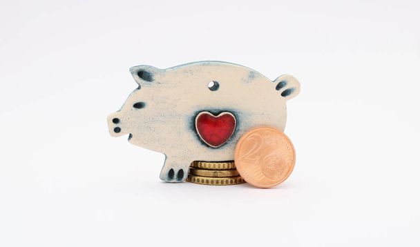 Керамічна свиня з монетами євро ізольована на білому тлі. Збереження
. - Фото, зображення