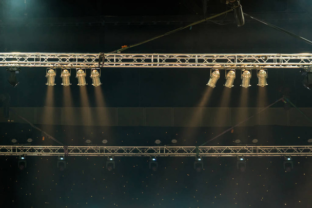 Lichtstrahlen der Konzertbeleuchtung vor dunklem Hintergrund über der Projektorleinwand, Musikinstrumentenkonzept - Foto, Bild