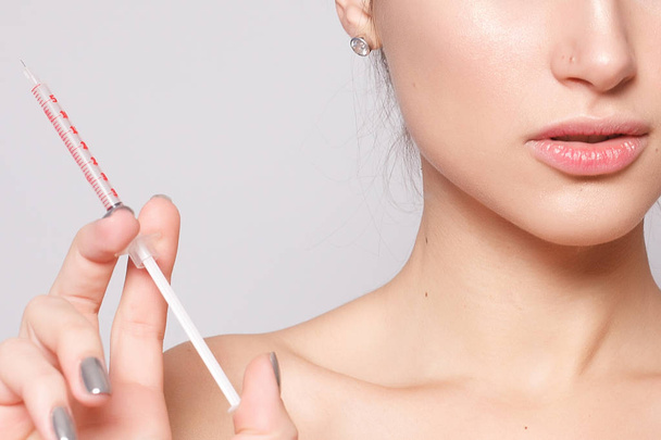Attractive young woman gets cosmetic injection, isolated over white background. female hand holds a syringe for injection near face. Beauty Treatment. - Φωτογραφία, εικόνα