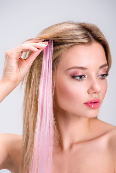 attractive young woman applying pink clip-on hair strand isolated on grey - Fotoğraf, Görsel