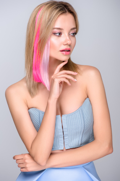 attraktive junge Frau mit farbigen Haarsträhnen und stylischem Korsett, die isoliert auf grau schaut - Foto, Bild