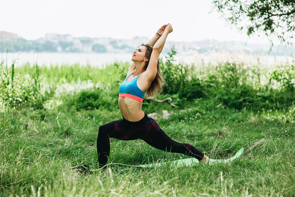 Sportive young woman in sportswear doing exercises outdoors - Photo, image