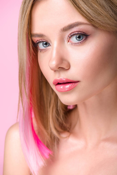 close-up portrait of attractive young woman with colorful hair strands looking at camera isolated on pink - 写真・画像