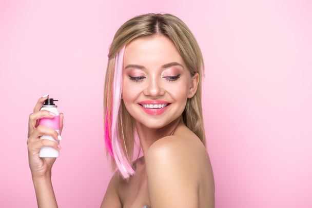 mujer joven feliz con hebras de colores de pelo y pintura en aerosol aislado en rosa
 - Foto, Imagen
