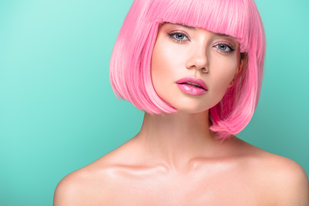 atractiva mujer joven con corte bob rosa y maquillaje elegante mirando a la cámara aislada en turquesa
 - Foto, Imagen