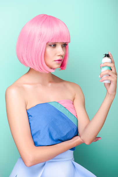κομψό νεαρή γυναίκα με ροζ bob περικοπή κατέχουν σπρέι μαλλιών χρωματισμού που απομονώνονται σε τυρκουάζ - Φωτογραφία, εικόνα