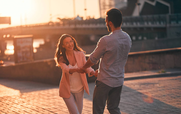 Love is in the air! Cute romantic couple spending time together in the city. Handsome bearded man and attractive young woman are in love. Dancing during sunset. - Photo, image