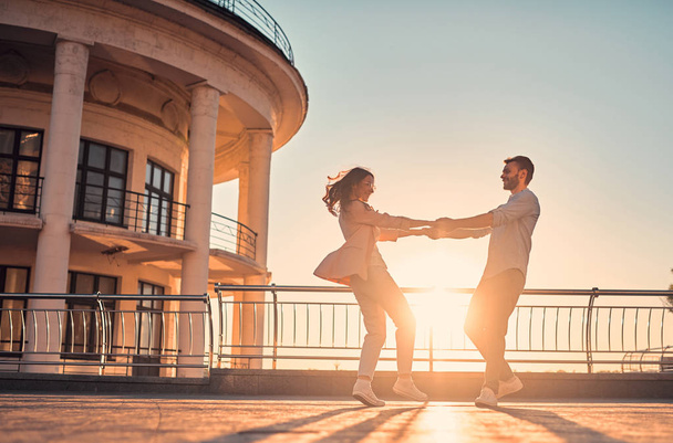 Love is in the air! Cute romantic couple spending time together in the city. Handsome bearded man and attractive young woman are in love. Hugging, kissing and having fun during the sunset. - Fotografie, Obrázek