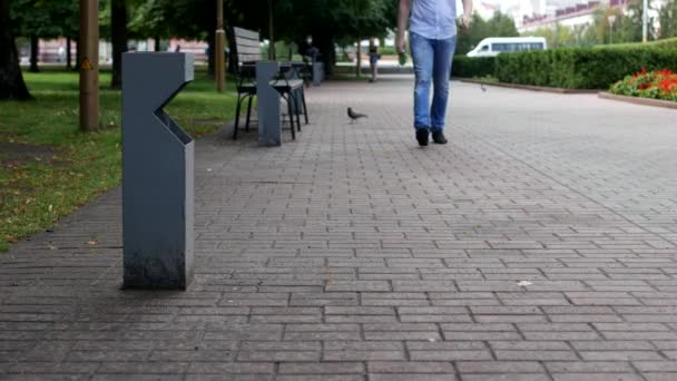 a man walks down the street and throws a plastic bottle by the garbage - Materiał filmowy, wideo