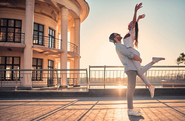 Love is in the air! Cute romantic couple spending time together in the city. Handsome bearded man and attractive young woman are in love. Hugging, kissing and having fun during the sunset. - Photo, image