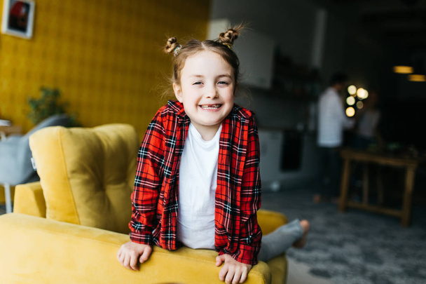 Photo of little girl at sofa on blurred background - Foto, afbeelding