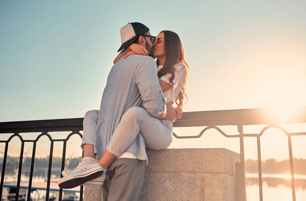 Love is in the air! Cute romantic couple spending time together in the city. Handsome bearded man and attractive young woman are in love. Hugging, kissing and having fun during the sunset. - Zdjęcie, obraz