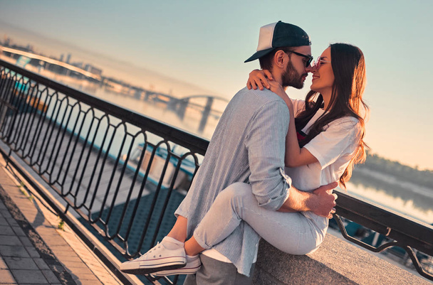 Love is in the air! Cute romantic couple spending time together in the city. Handsome bearded man and attractive young woman are in love. Hugging, kissing and having fun during the sunset. - Photo, Image