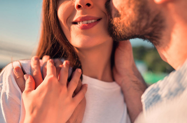 Love is in the air! Cropped image of cute romantic couple spending time together in the city. Handsome bearded man and attractive young woman are in love. Hugging, kissing and having fun during the sunset. - Fotó, kép
