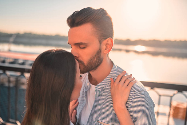 Love is in the air! Cute romantic couple spending time together in the city. Handsome bearded man and attractive young woman are in love. Hugging, kissing and having fun during the sunset. - Foto, immagini