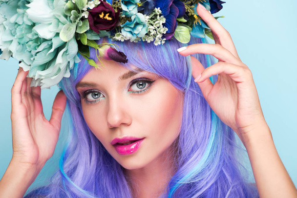 close-up portrait of young woman with curly blue hair and floral wreath isolated on blue - Fotografie, Obrázek