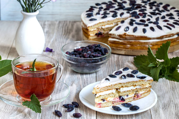 Cake with honeysuckle and tea on a wooden table. - Photo, Image