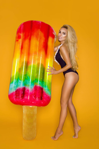 schöne, sexy Frau mit langen blonden Haaren, trägt einen Bikini und hält eine Schwimmmatratze - Foto, Bild