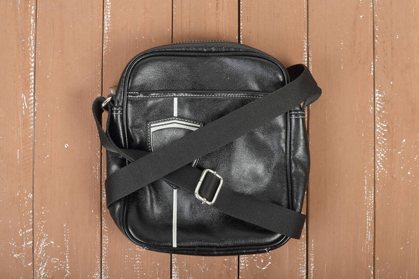 Kleding, schoenen en accessoires - bovenaanzicht zwart leer man de zak op een houten achtergrond - Foto, afbeelding