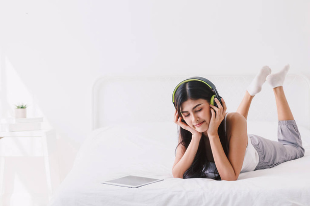 Γυναίκα ακούτε μουσική με ακουστικά σε κρεβάτι - Φωτογραφία, εικόνα