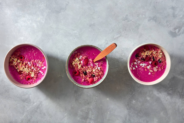 smoothie with granola, beetroot  and berries in ceramic bowls with wooden spoon, healthy breakfast  - Zdjęcie, obraz