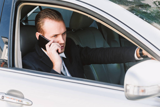 Empresario utilizar el teléfono inteligente mientras conduce el coche
 - Foto, Imagen