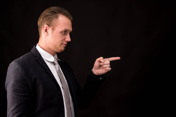 Homme d'affaires pointant vers l'espace de copie vide sur fond noir
 - Photo, image