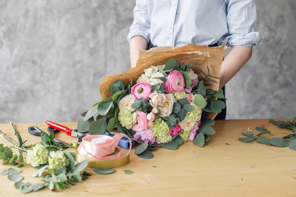 Woman florist creating beautiful bouquet in flower shop. Working in flower shop. Girl assistant or owner in floral design studio, making decorations and arrangements. - Photo, Image