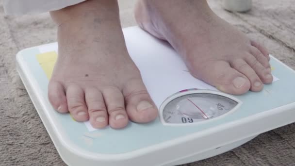 Donna anziana in piedi su bilancia di peso, il suo peso misura 54 kg
. - Filmati, video
