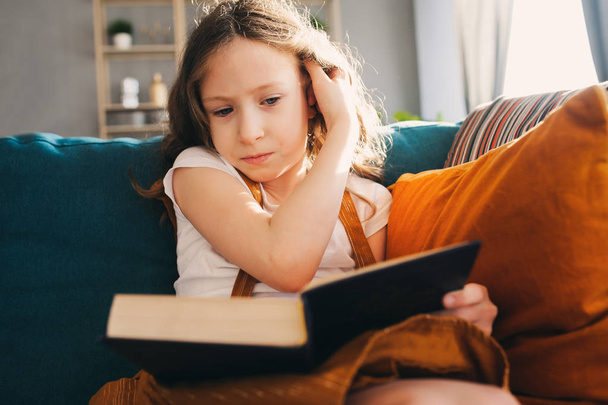 concentrated child girl reading interesting book at home - 写真・画像