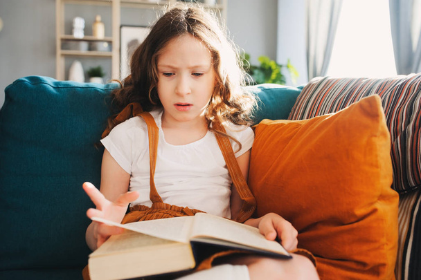 concentrated child girl reading interesting book at home - 写真・画像
