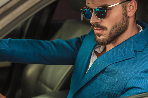 portrait of attractive smart casual man with sunglasses driving his car, sitting on driver's seat - Photo, image