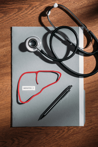 top view of folder, stethoscope, and liver with lettering hepatitis c on table, world hepatitis day concept - Photo, Image