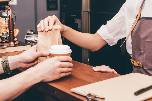 Barista kobieta podając filiżankę kawy do klienta w kawiarni - Zdjęcie, obraz