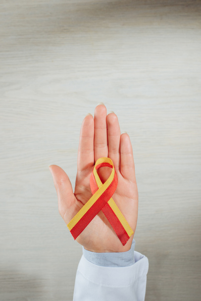 cropped image of female doctor holding ribbon over table, world hepatitis day concept - Photo, Image