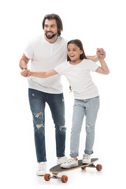 father helping little daughter skating on skateboard isolated on white - Photo, Image