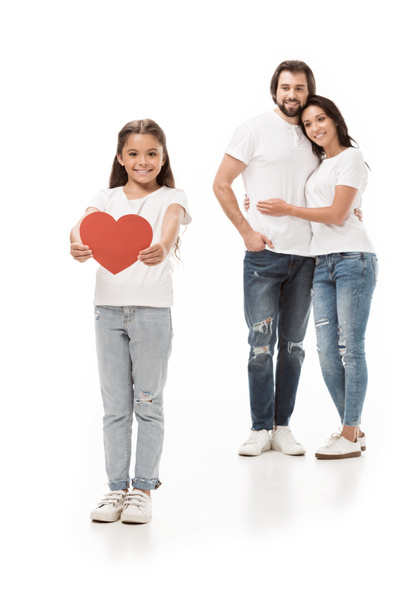 smiling kid showing red paper heart with parents hugging behind isolated on white - Photo, Image