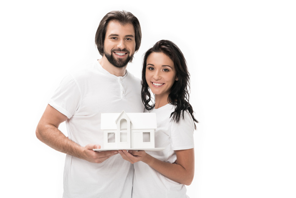 retrato de pareja sonriente con modelo de casa aislado en blanco
 - Foto, imagen