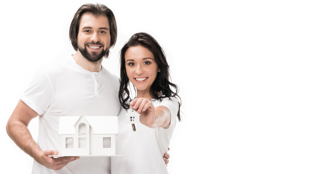portrait of smiling couple with house model and keys isolated on white - Foto, Imagen