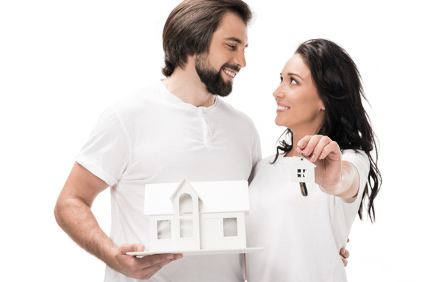 selective focus of smiling couple with house model and keys isolated on white - Fotografie, Obrázek